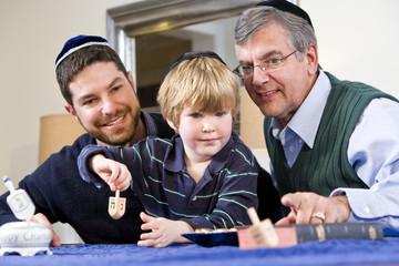 Boy with father and grandfather spinning dreidel