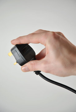 Hand holding UK 3 pin plug