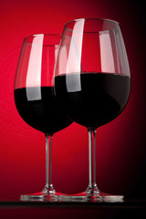 Two glasses of red wine on a red background