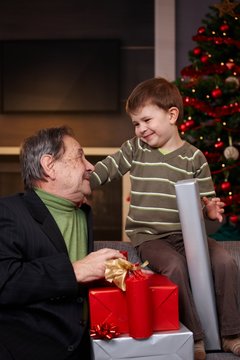 Young boy getting christmas present from grandfather