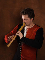 Man in a medieval suit plays a flute © Demian