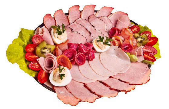 Dish with sliced smoked ham, salami rolls, boiled eggs.