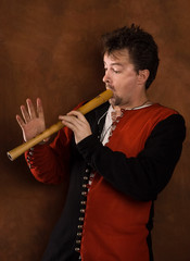 Man in a medieval suit plays a flute © Demian