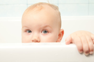 cute cheerful baby looking from bath hideout