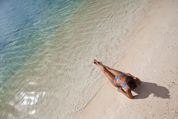 Woman sunbathing on white sand beach of a paradise island