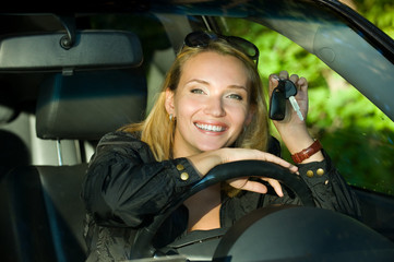 young happy woman in the new car with keys - outdoors