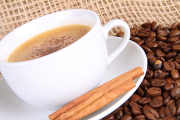 Cup of coffee with cinnamon sticks,beans and burlap material