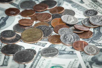 coins over hundred dollar bills close up