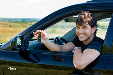 happy man showing keys from new car