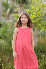 Cute girl in a pink dress in the park