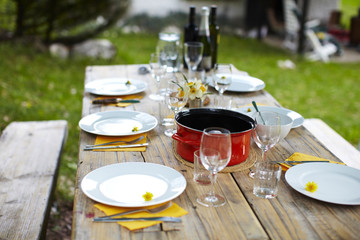 Picnic table set for lunch with dandelion flowers and wine.