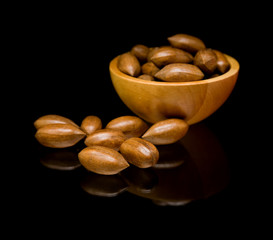 pecan nuts in small wooden bowl and scattered