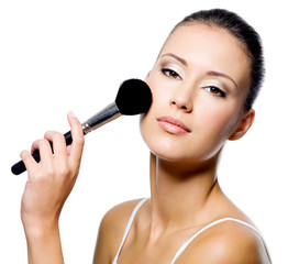 woman applying powder on cheek with brush