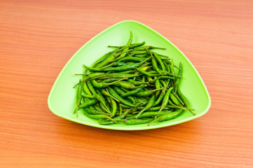 Hot peppers in the plate on wooden table