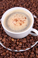 Cup of coffee with cinnamon with coffee beans around it