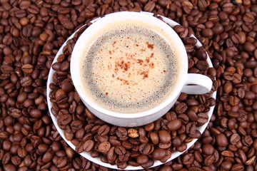 Cup of coffee with cinnamon with coffee beans around it