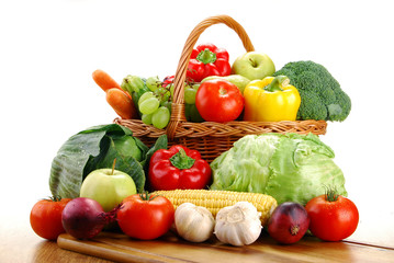 Composition with vegetables and wicker basket on kitchen table