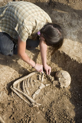 Archaeologist excavating a grave buried skeleton