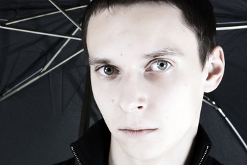Portrait of a young dark-haired man under umbrella
