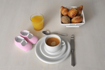 pregnancy concept baby shoes on the breakfeast table