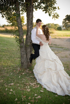 just married couple standing and kissing against a tree