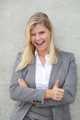 Blond businesswoman standing against a wall