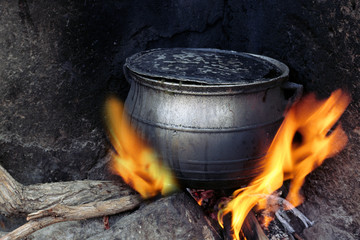 Sooty black coocking pot heated on fire