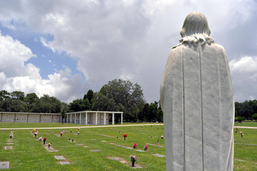 Statue of a Saint watching over the headstones at a cemetery