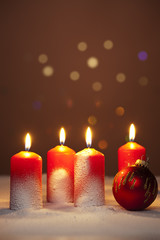 Adventskerzen und Christbaumkugel im Schnee