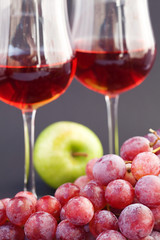 a glass of wine, apple and grape on a black background