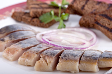herring with crackers on a plate. object on a white background