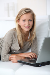 Blond girl sitting in sofa surfing on internet