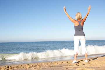 Senior Woman In Fitness Clothing Stretching On Beach