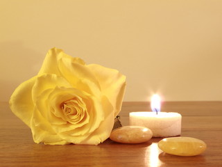 Kerze neben gelber Rose