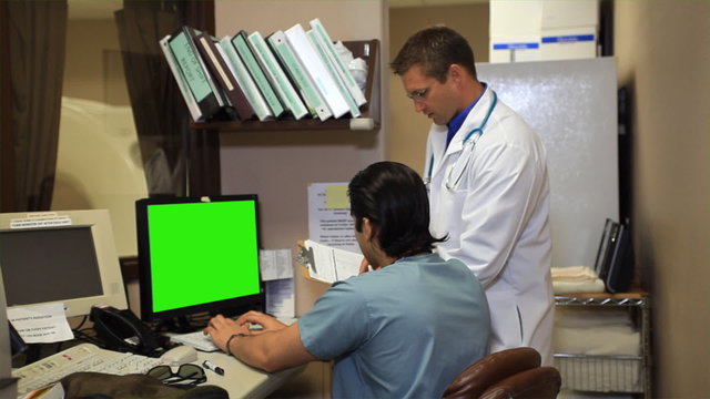 Health care providers at computer smile for camera.