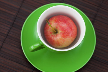 cup, saucer and apples on a bamboo mat
