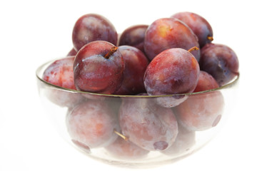 plums in a glass bowl isolated on white