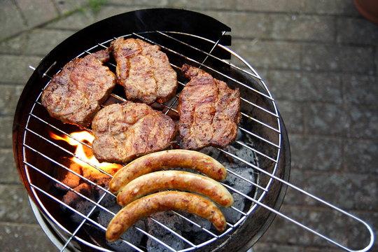 Grill mit Grillfleisch und Bratwurst im Garten