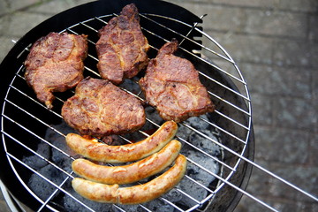 Grill mit Grillfleisch und Bratwurst im Garten