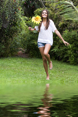 Mujer joven corriendo con flor amarilla
