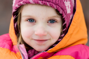 Winter toddler girl in pink hat looking to the camera