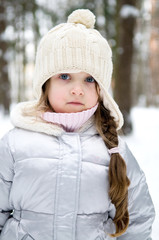 Adorable toddler girl with blue eyes in white warm hat