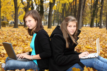 teenagers with a computer in the autumn park