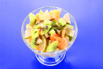 Cup with orange, kiwi and lime on blue