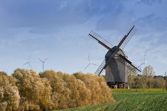 Alte Windmühle vor modernen Windkraftanlagen
