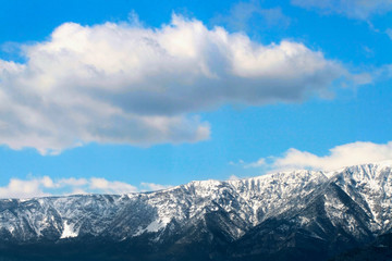 Winter mountains below blue cloudy sky