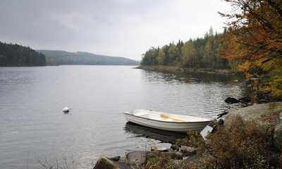 Rainy lake landscape with white boat