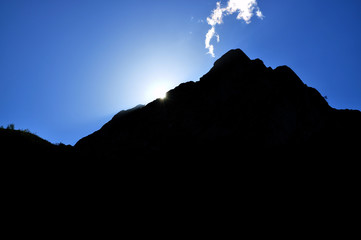 Bright sun at sunset, hiding behind the mountain, sparkling rays
