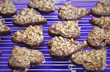 Chocolate cookies with nuts shaped as hearts cooling on a wire