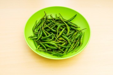 Hot peppers in the plate on wooden table